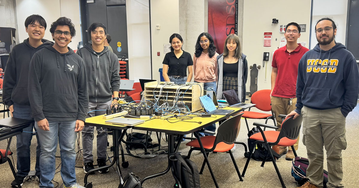 Team of college students around a table of computer hardware.