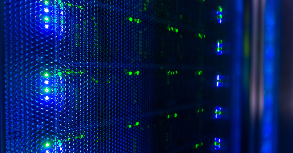 Server rack with glowing green status indicator lights and blue lighting behind a perforated metal panel.